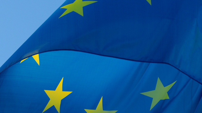 Europaflagge vor blauem Himmel, links oben ist das weiße ZdK-Kreuz-Logo